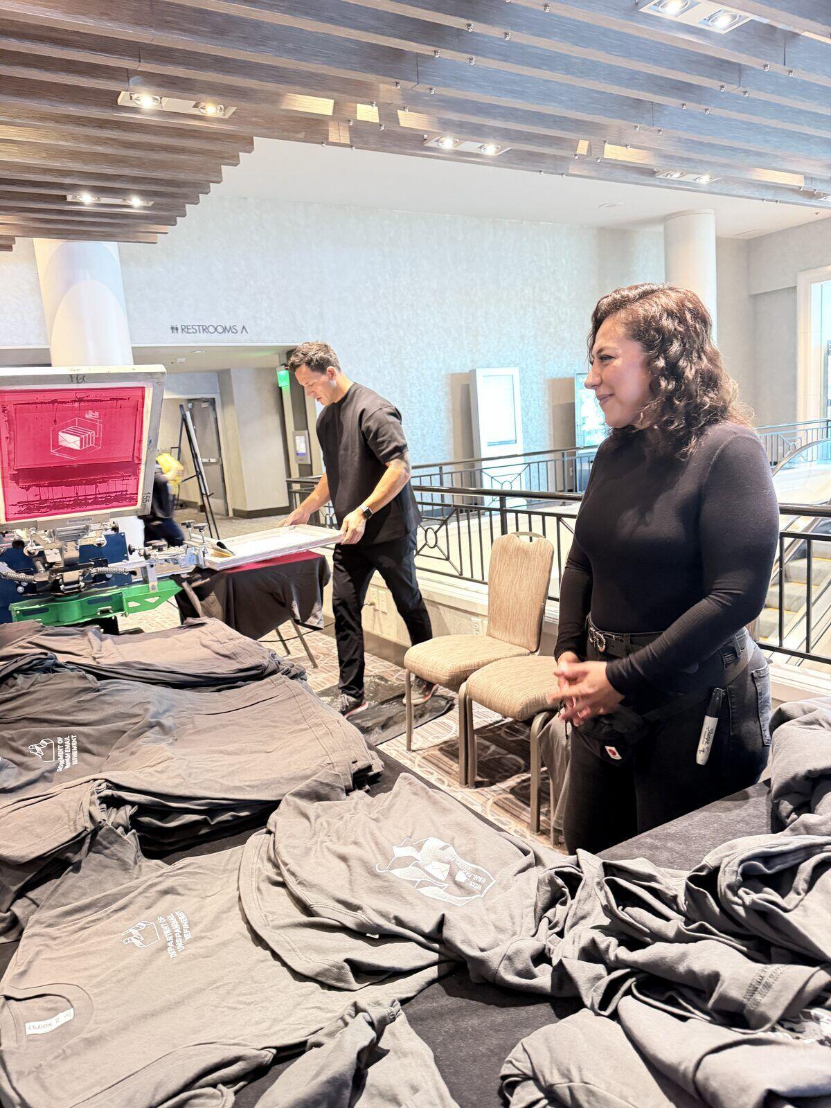 Crew setting up printing equipment and tables on load-in day before an event opens