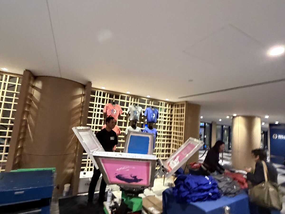 Compact printing station set up in a building lobby with equipment and product staged on tables